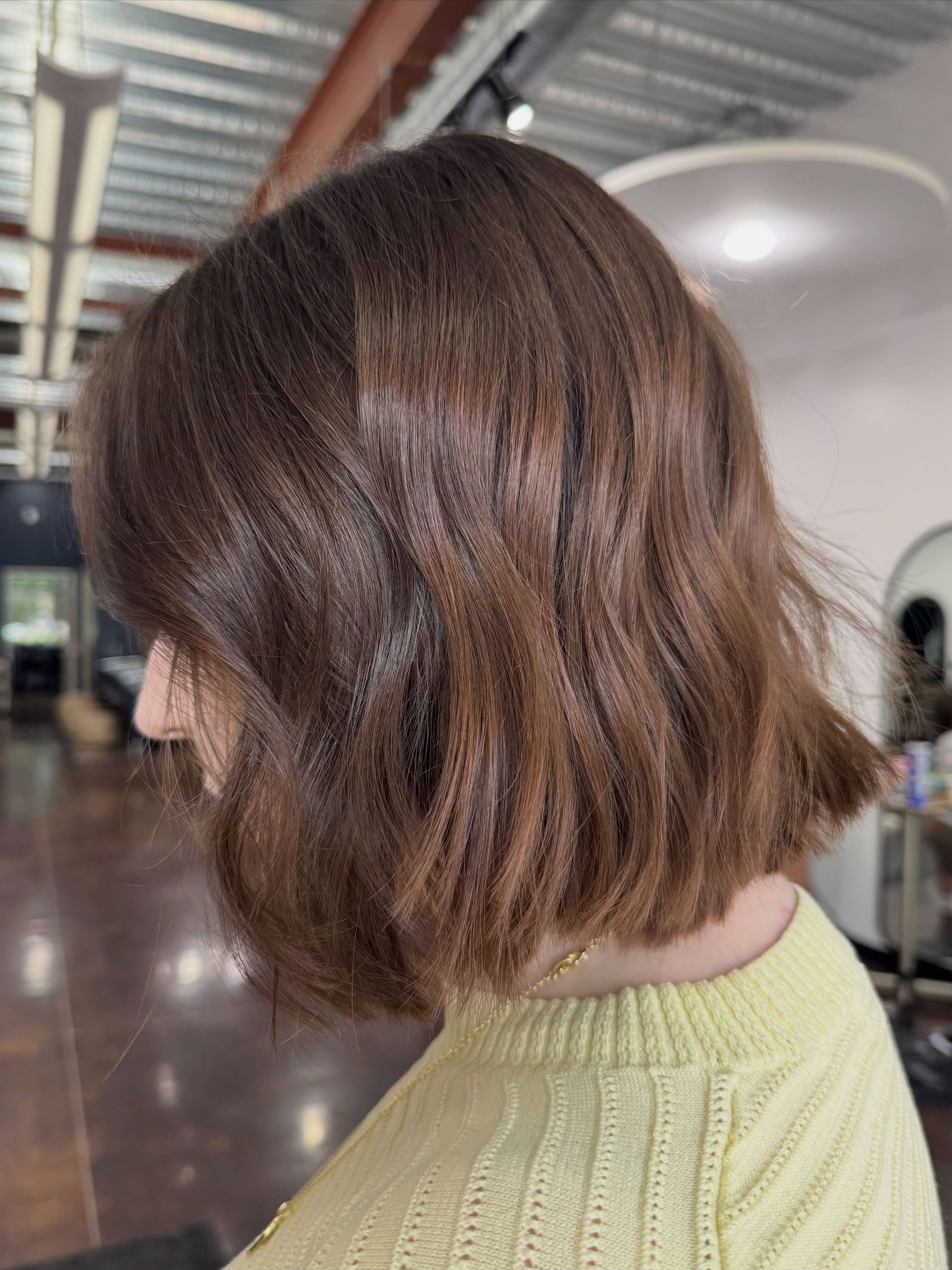Side profile of a person with short brown hair in a light green sweater indoors