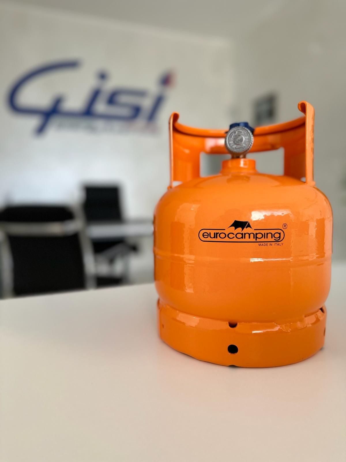 Una bombola di propano portatile di colore arancione con il logo del marchio Eurocamping, appoggiata su un tavolo bianco in un ambiente d'ufficio.