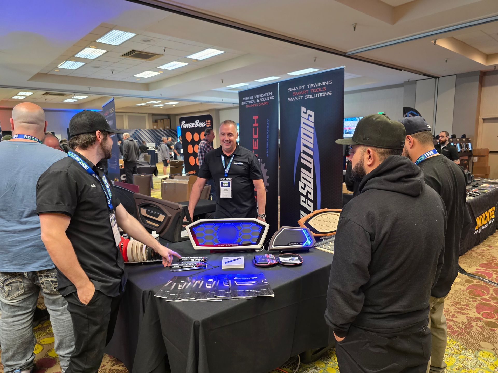 Attendees at a trade show booth featuring branded displays and merchandise engage in conversation.