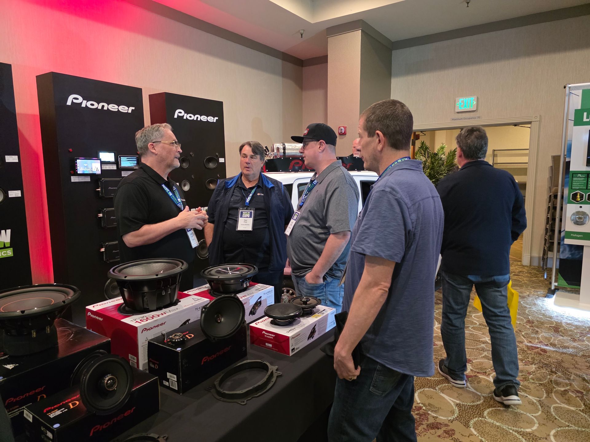 Four people stand around a table displaying Pioneer audio equipment in a room at an industry trade show.