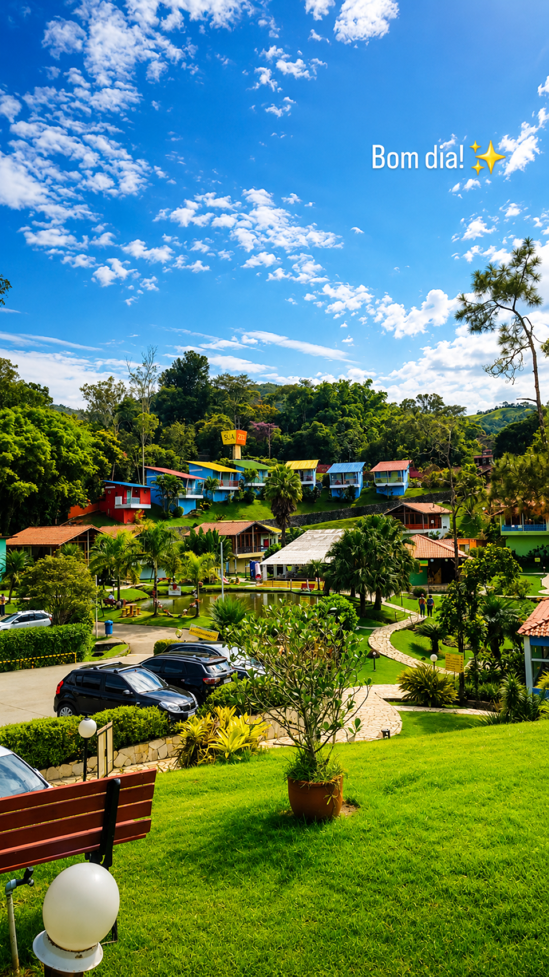 Resort em uma encosta verdejante, com cabanas coloridas, árvores e céu azul com nuvens.
