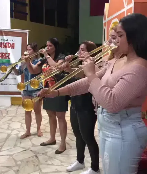 Quatro músicos tocam instrumentos de sopro em um palco fechado durante uma apresentação.