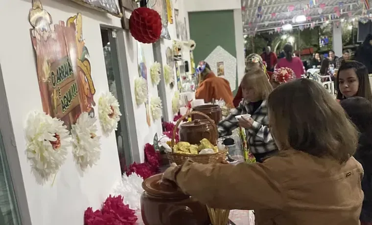Pessoas observam uma mesa de exposição interna decorada com flores, velas e itens festivos.