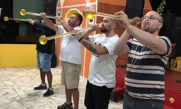 Quatro homens tocando instrumentos de sopro ao ar livre sob luzes coloridas perto de um prédio.