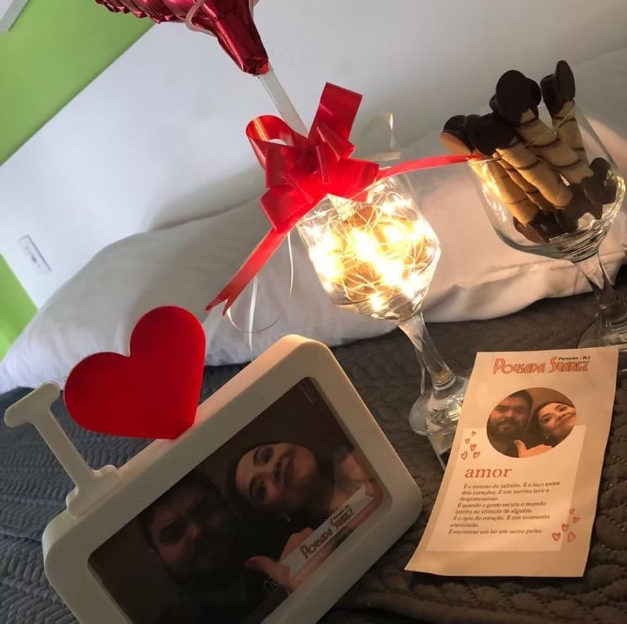 Arranjo memorial de mesa com decoração em forma de coração, copo à luz de velas, foto emoldurada e um pequeno cartão com o programa da cerimônia.