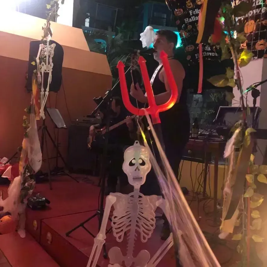 Palco para festa de Halloween com decoração de esqueletos, tridente vermelho como adereço e iluminação assustadora.