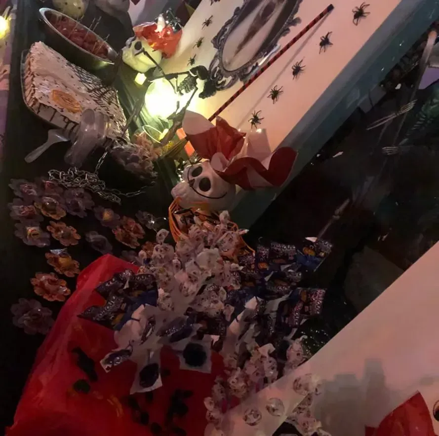 Quarto com tema de Halloween, com uma lâmpada brilhante, decorações de caveira, flores e cortinas vermelhas.