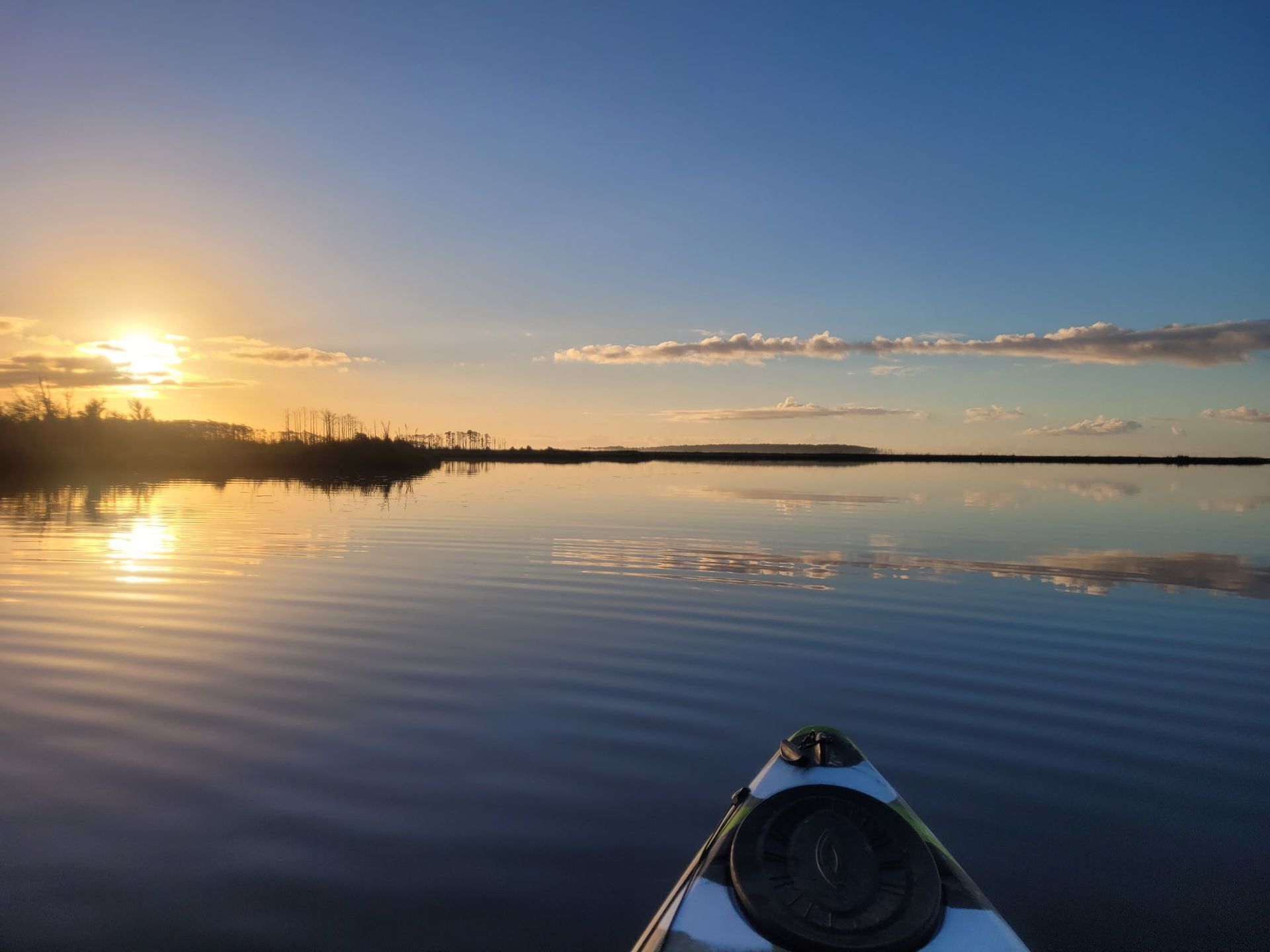 Kayak on calm water at sunset, with golden reflections and a blue sky