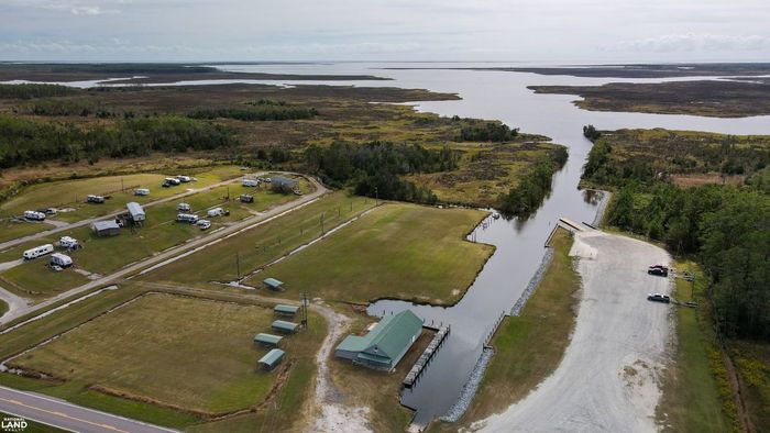 Aerial view of a riverside campground with RVs, cabins, and a winding river bordered by green forest.