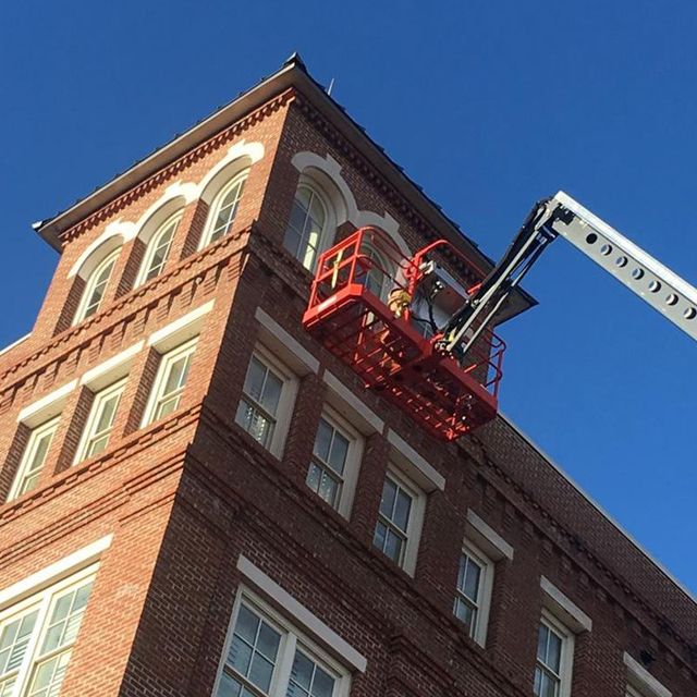 Worker on Lift Bucket Painting the Exterior of the Building