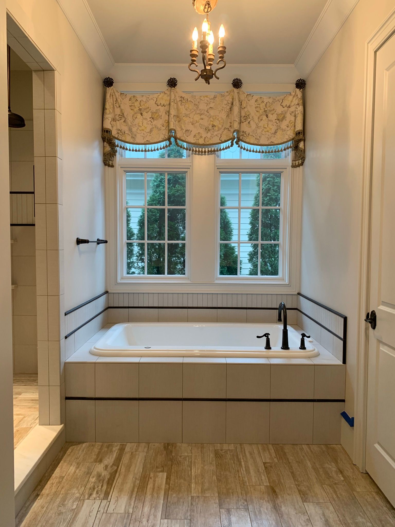 A bathroom with a bathtub and two windows.