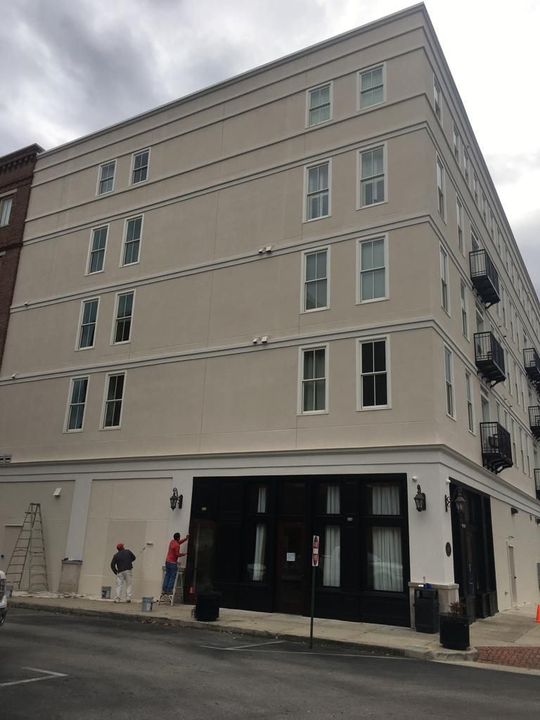 A large building with a lot of windows is on the corner of a street.