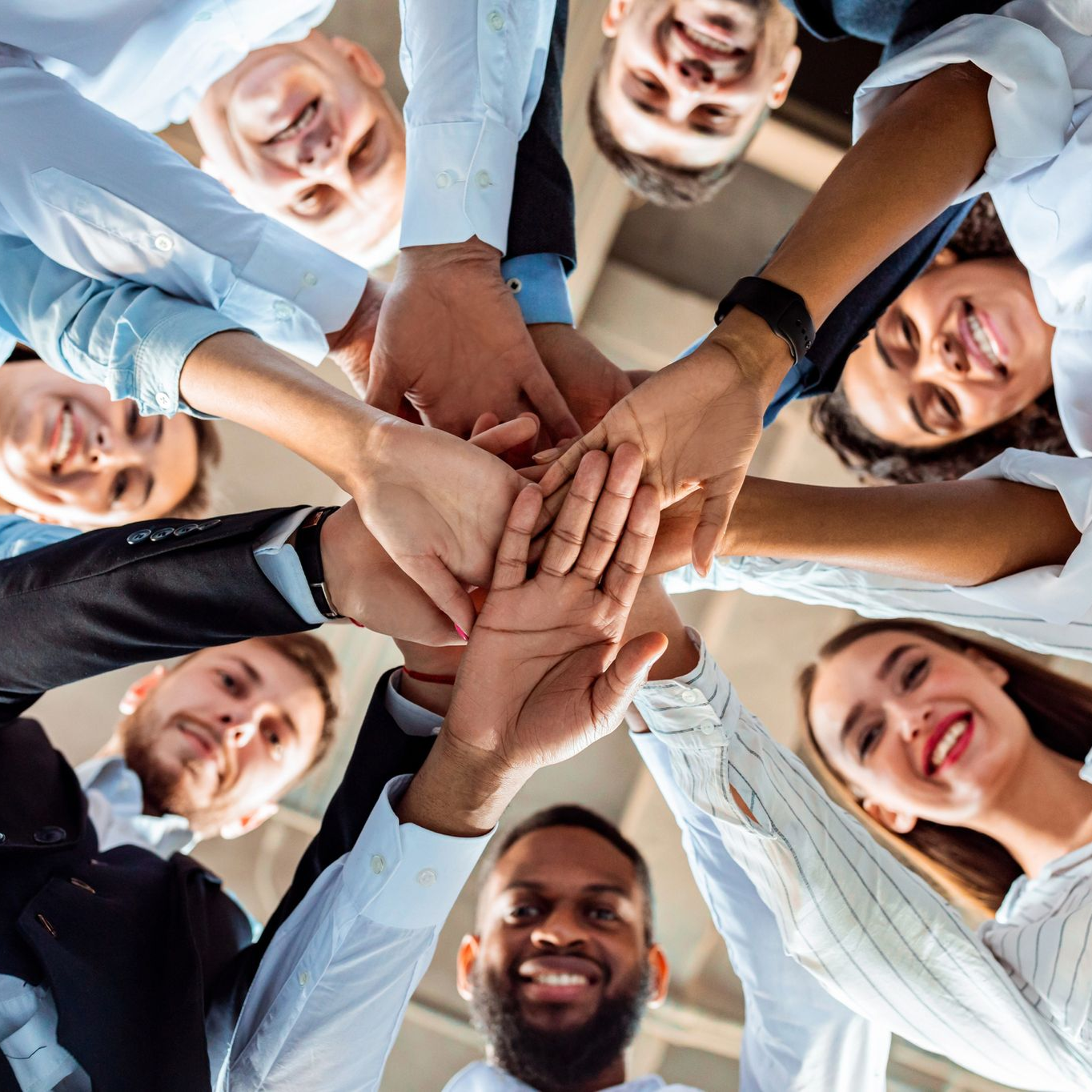 Un gruppo di persone diverse, con le mani giunte in cerchio, sorridenti, a dimostrazione di unità.