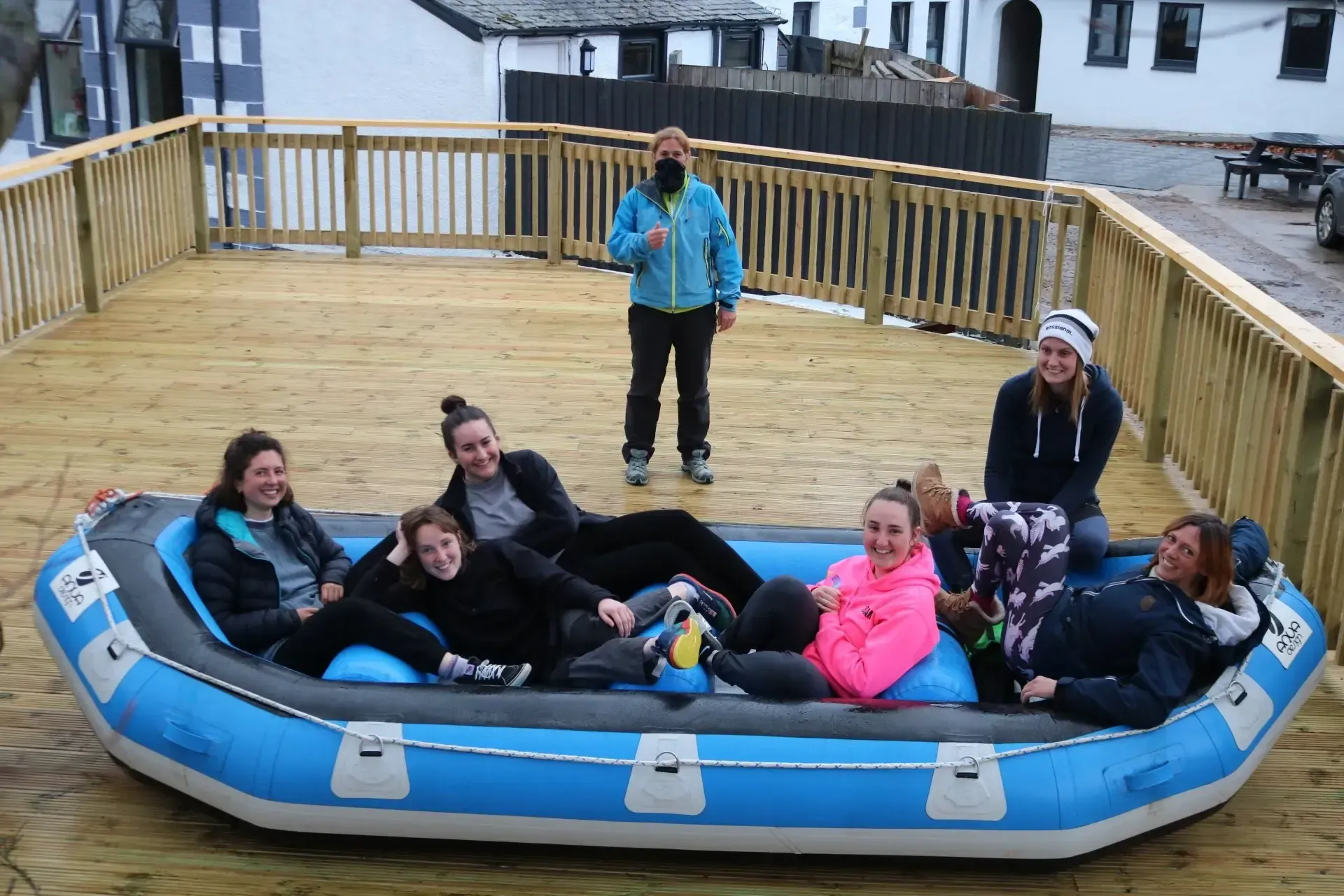 A group of people are laying on an inflatable raft on a deck.
