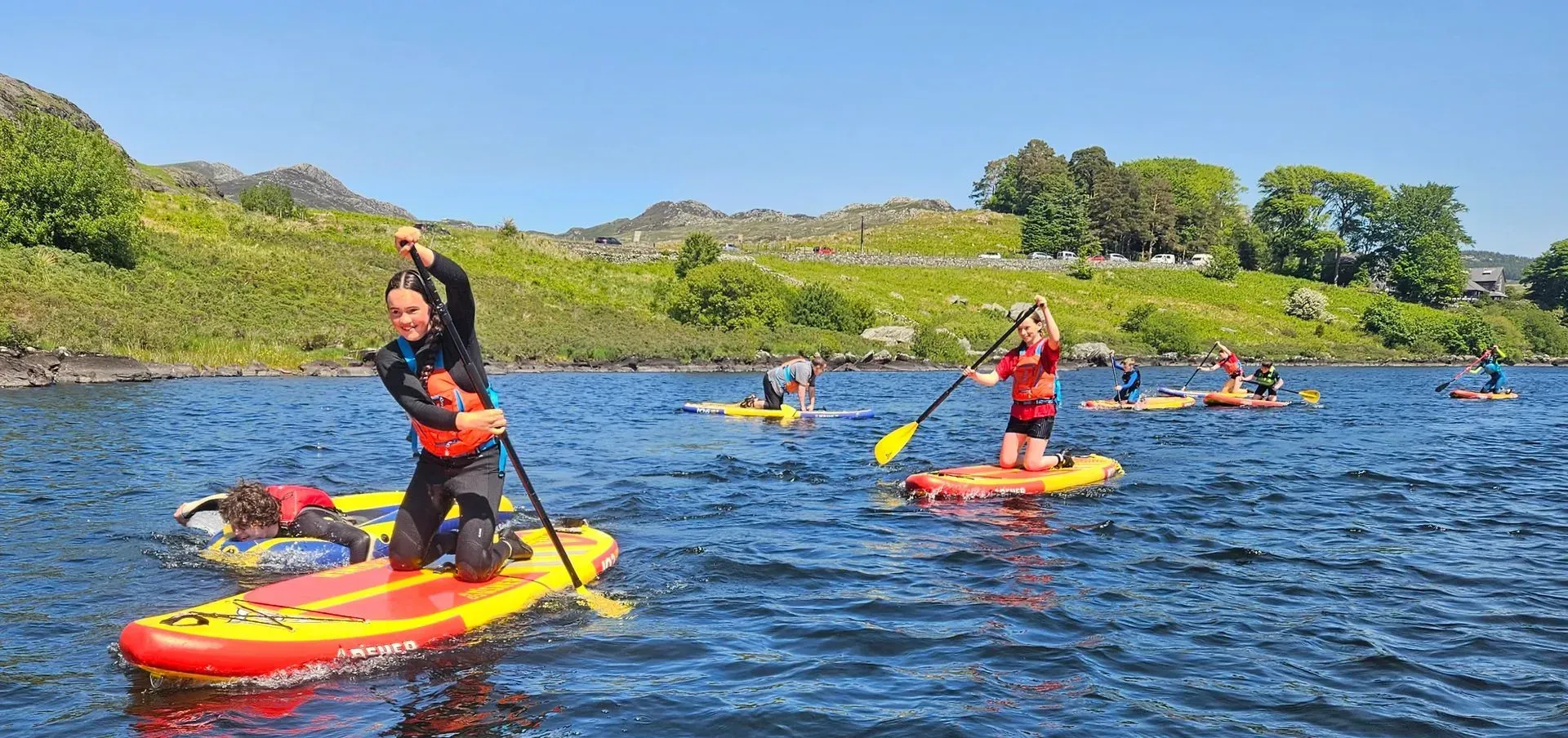 A group of people are riding paddle boards on a lake.