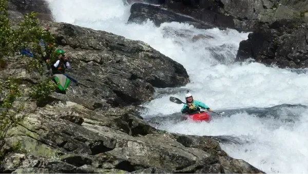 A man in a kayak is going down a waterfall.