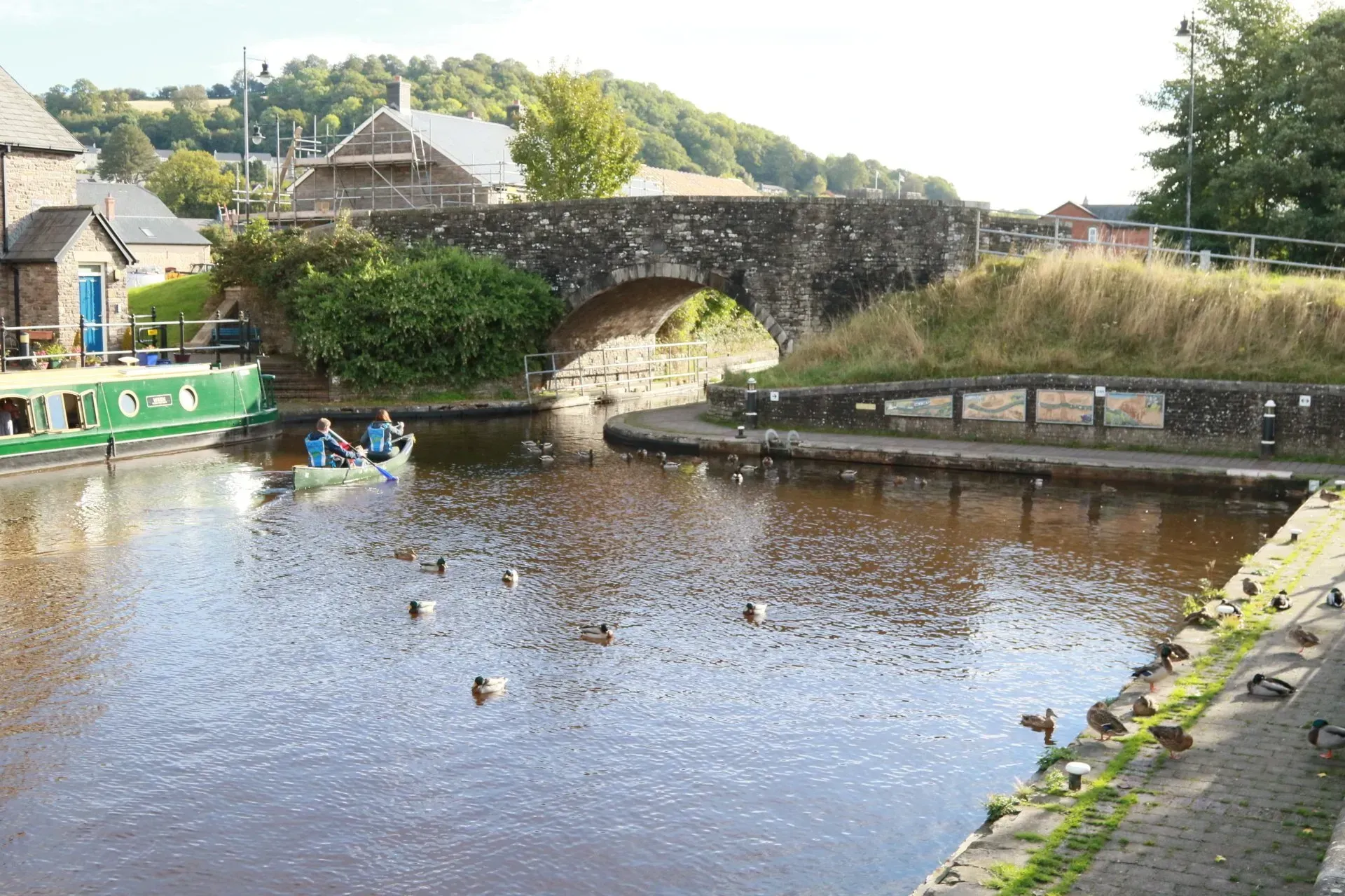 Pont dros afon gyda hwyaid yn nofio ynddi