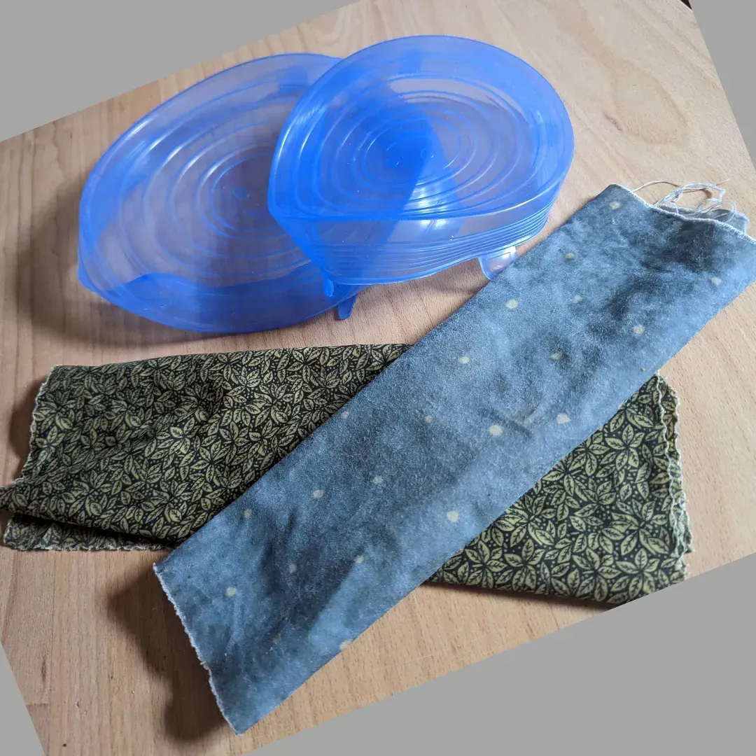 A blue plastic lid sits on a wooden table next to a piece of fabric