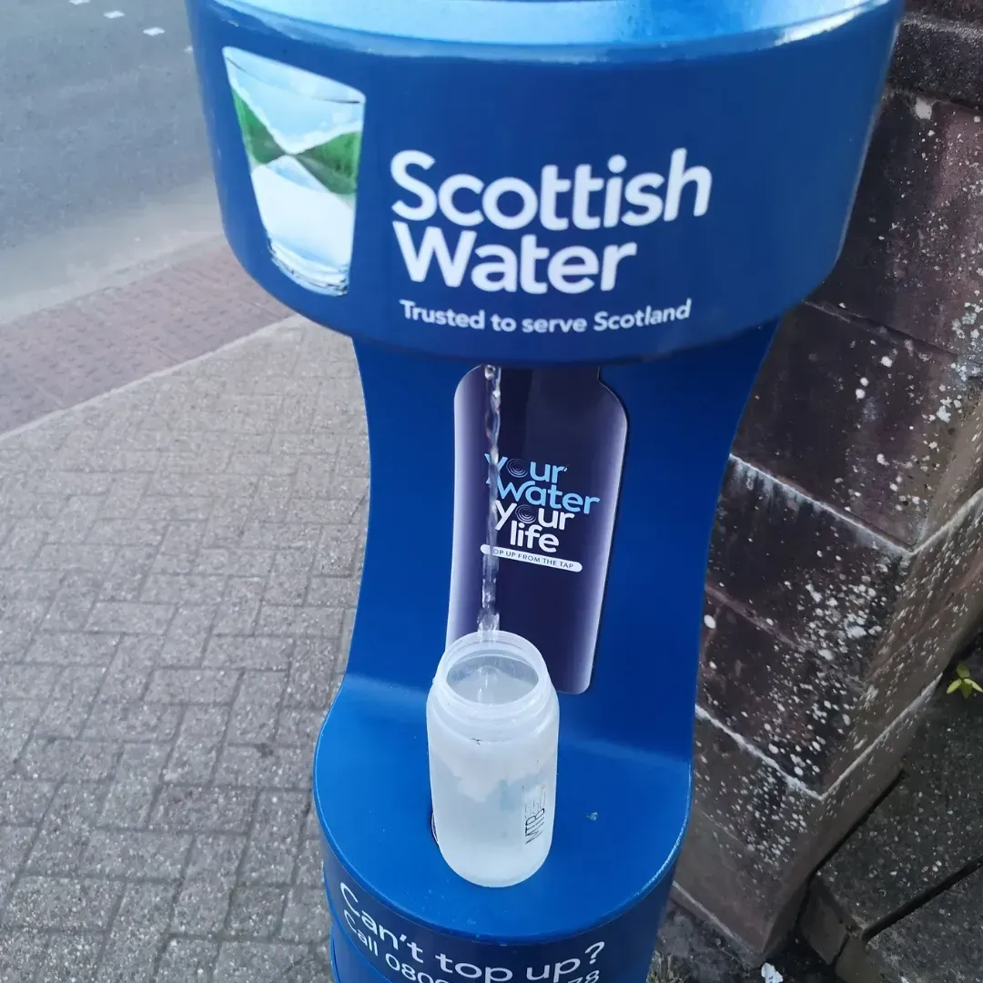 A blue scottish water dispenser with a bottle in it