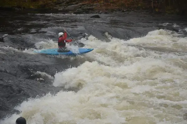 A person is riding a kayak down a river.