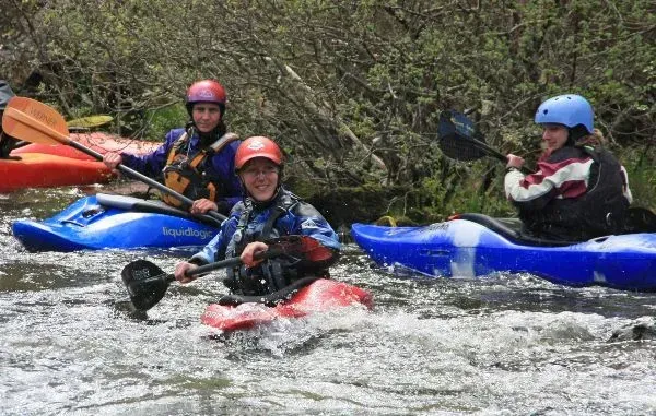 A group of people are riding kayaks down a river.
