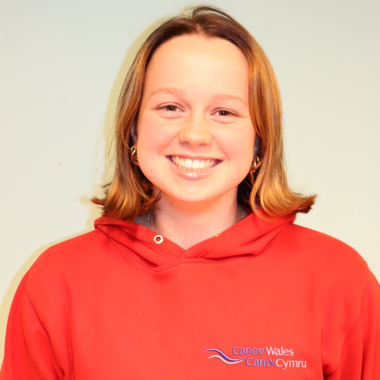 A woman wearing a red hoodie with the word wales on it