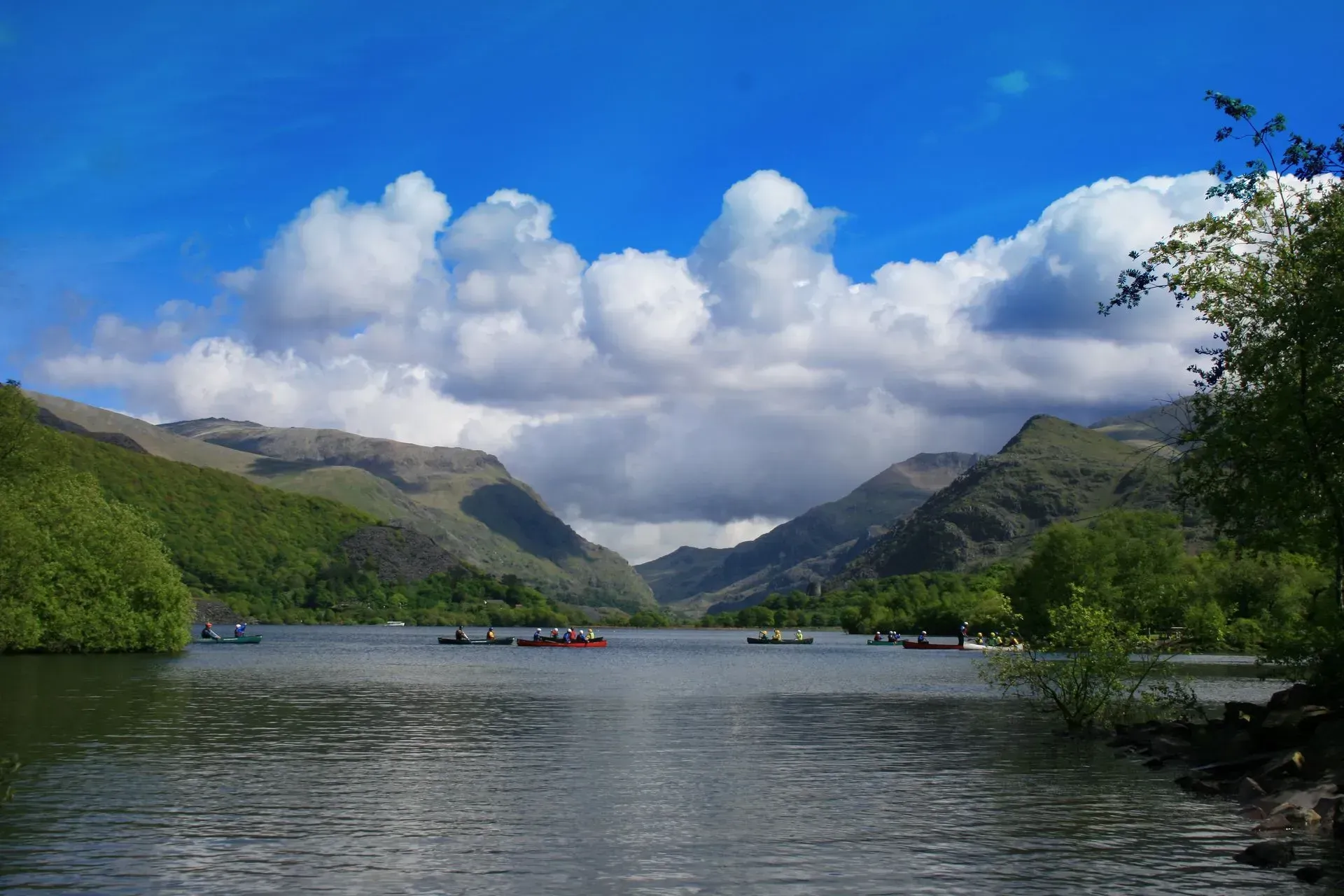 Llyn gyda mynyddoedd yn y cefndir a chychod yn y dwr