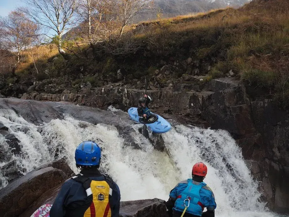 A man in a kayak is going down a waterfall.