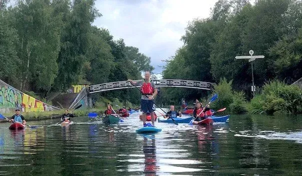 A group of people are riding kayaks down a river.