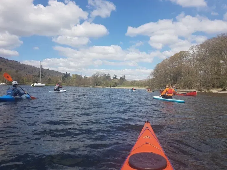 A group of people are rowing kayaks on a lake.