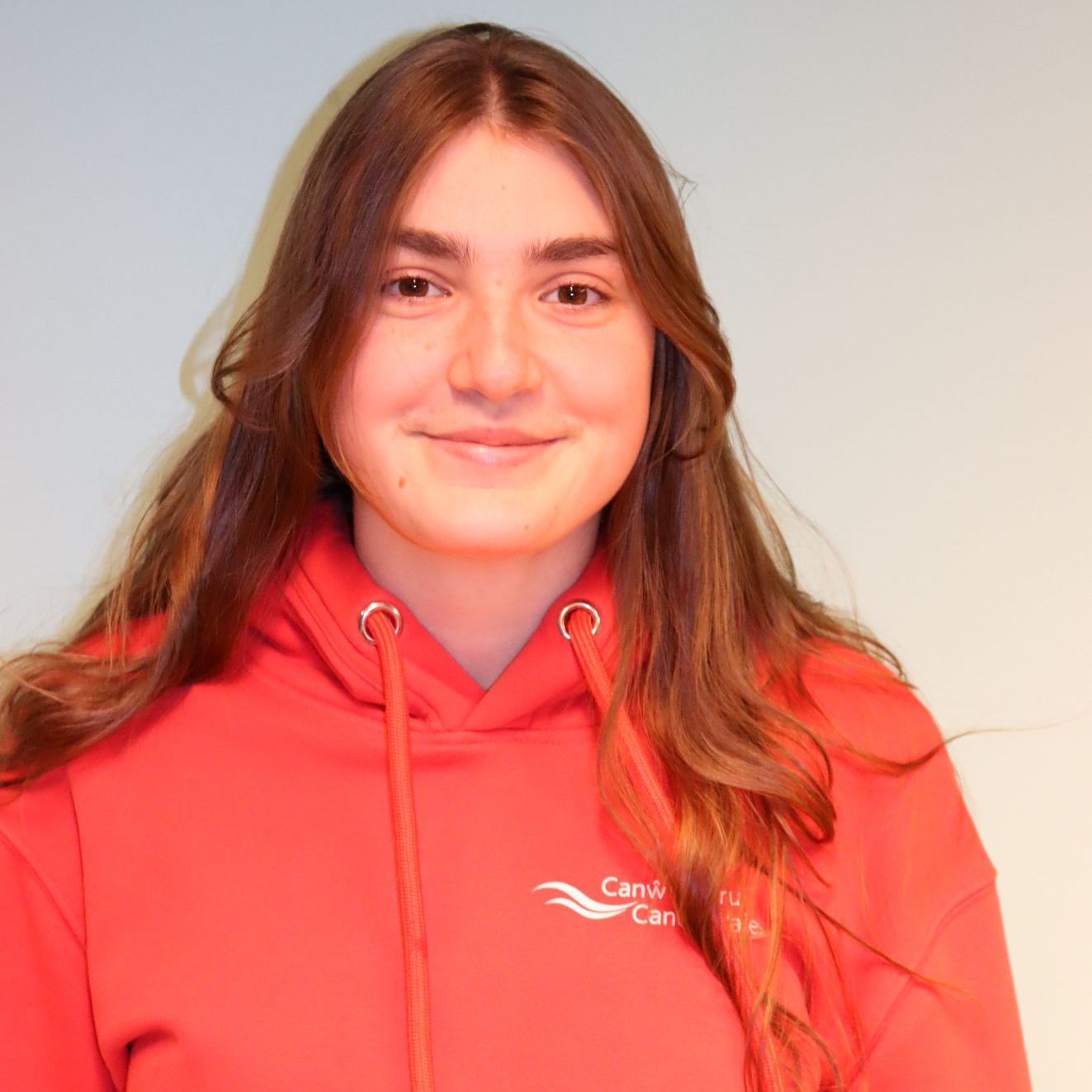 A woman wearing a red hoodie is smiling for the camera.