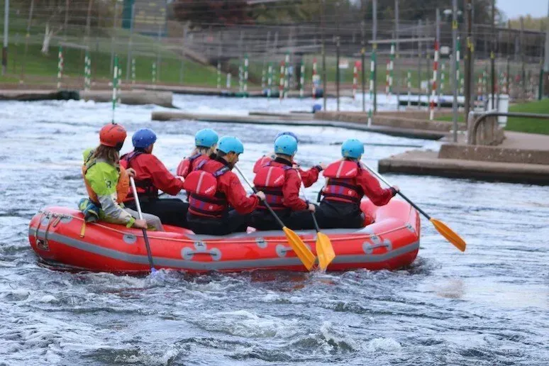 A group of people are rowing a red raft down a river.