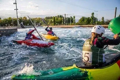 A group of people are rowing kayaks down a river.