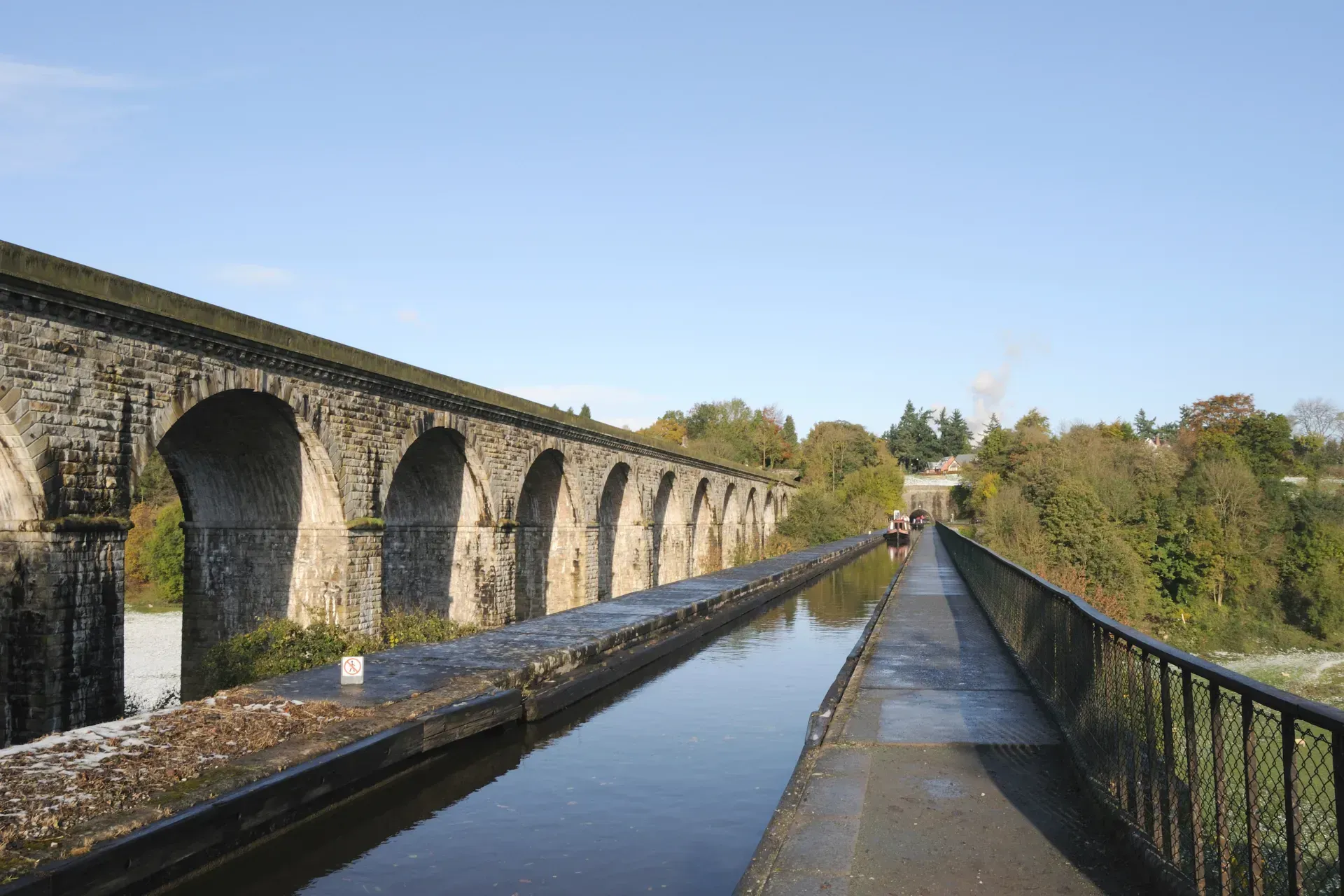 Pont dros gorff o ddŵr gyda choed yn y cefndir