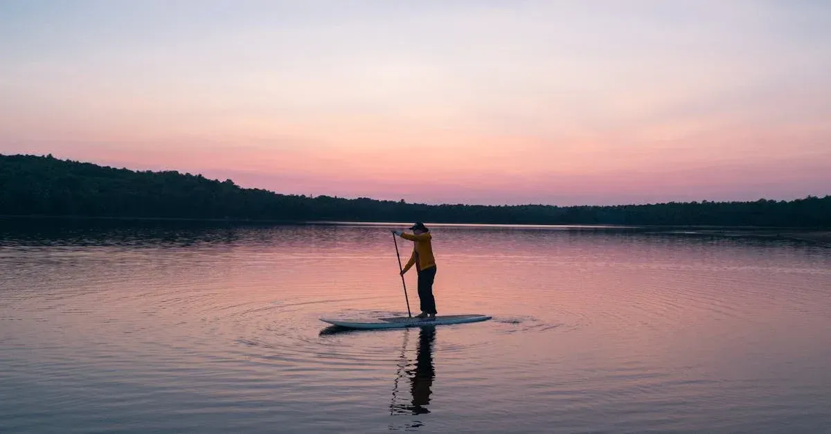 A person is riding a paddle board on a lake at sunset.