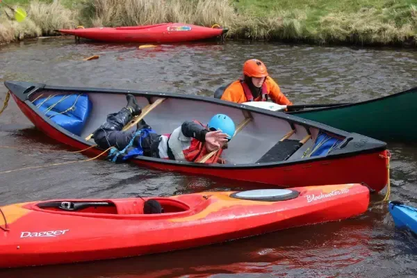 A group of people are rowing kayaks on a river.