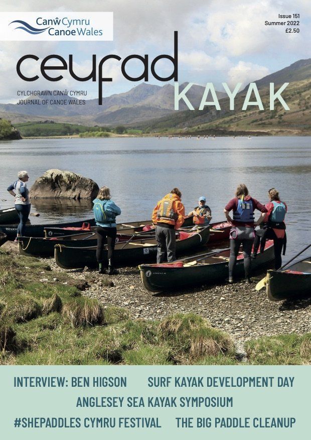 Mae criw o bobl yn sefyll mewn caiacau ar lan llyn.