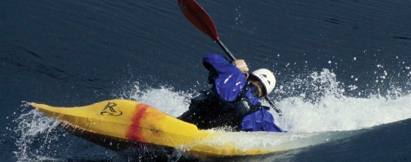 A person in a yellow kayak with a red paddle