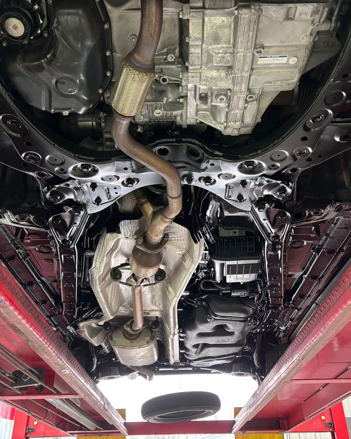 A person wearing black gloves is polishing the hood of a red car.