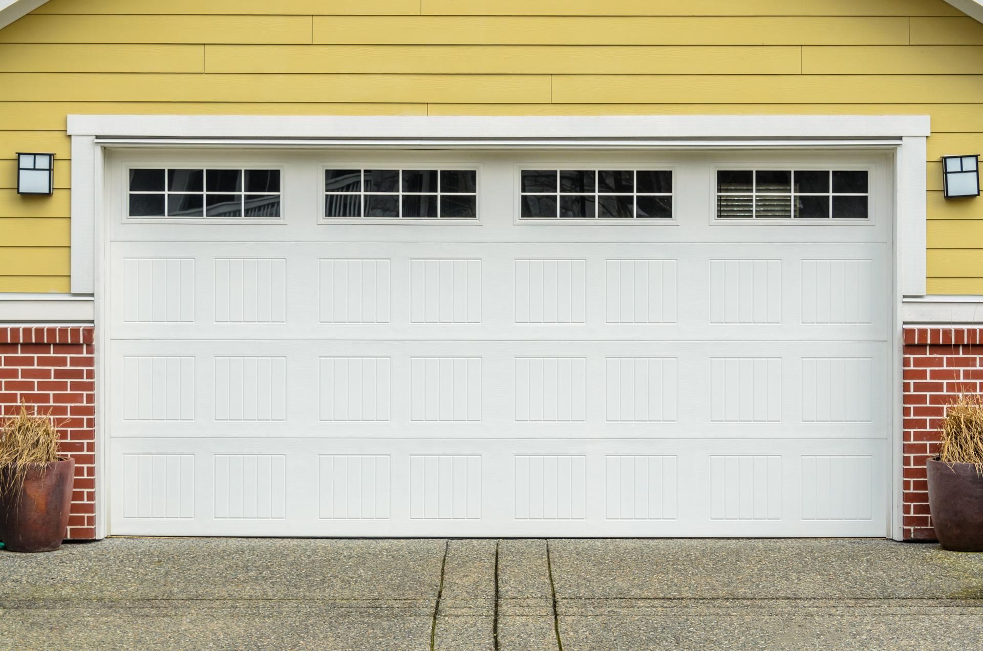 White garage door with windows, brick accents, and yellow siding.