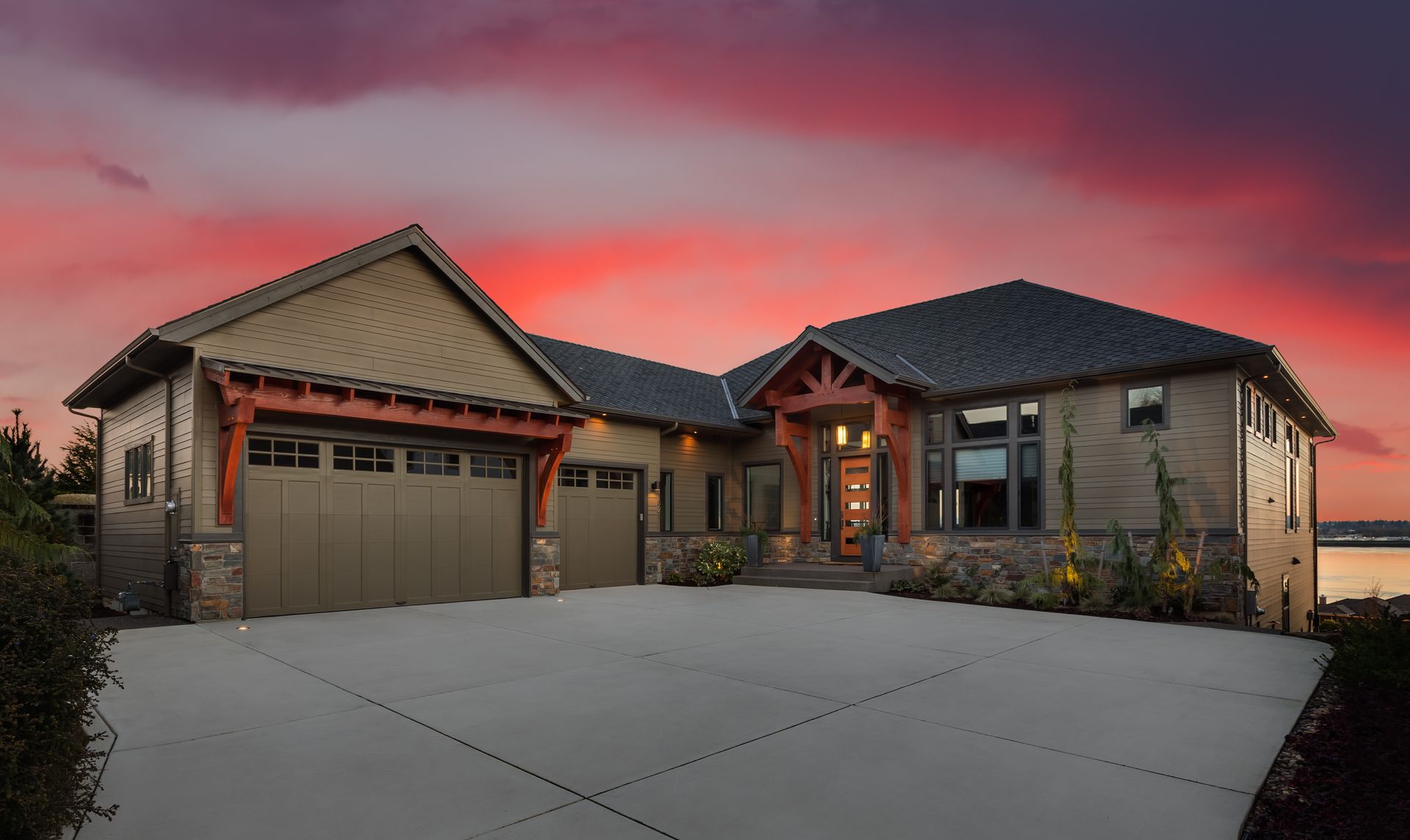 Modern single-story house with two-car garage at sunset, under a pink and purple sky