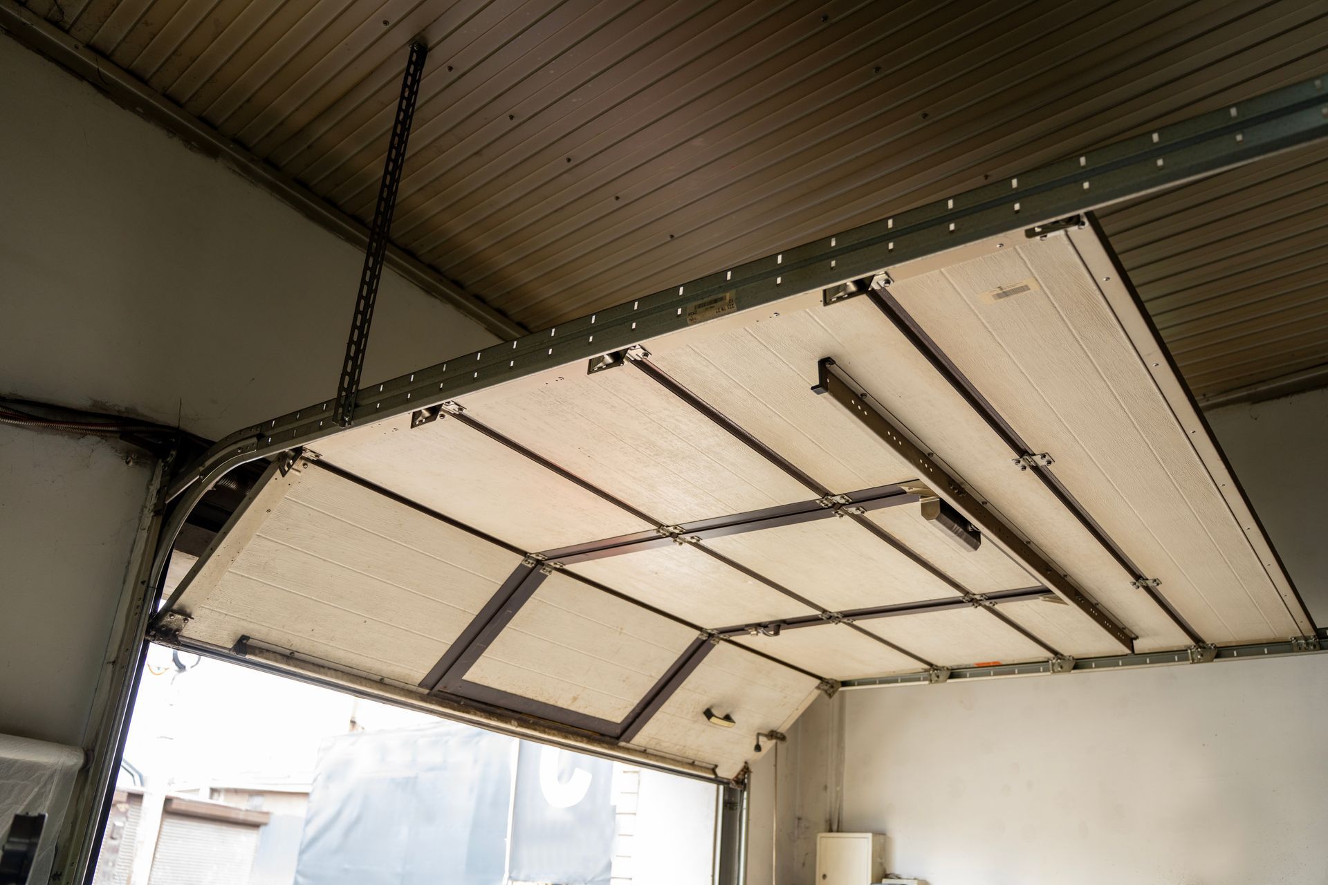 Garage door system installed inside residential garage with sectional overhead door panels-. Garage door system installed inside residential garage with sectional overhead door panels-.