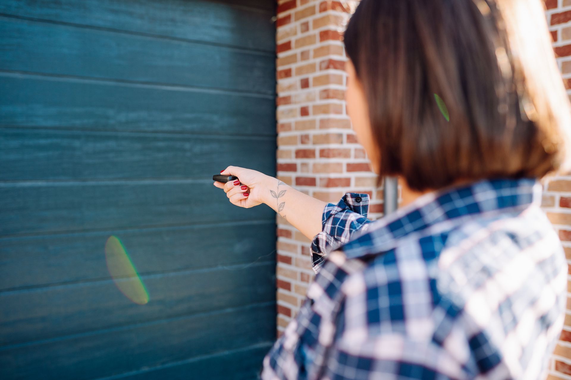 Woman use remote control to open garage gate - Garage Door System Repair In Orange County, Ca