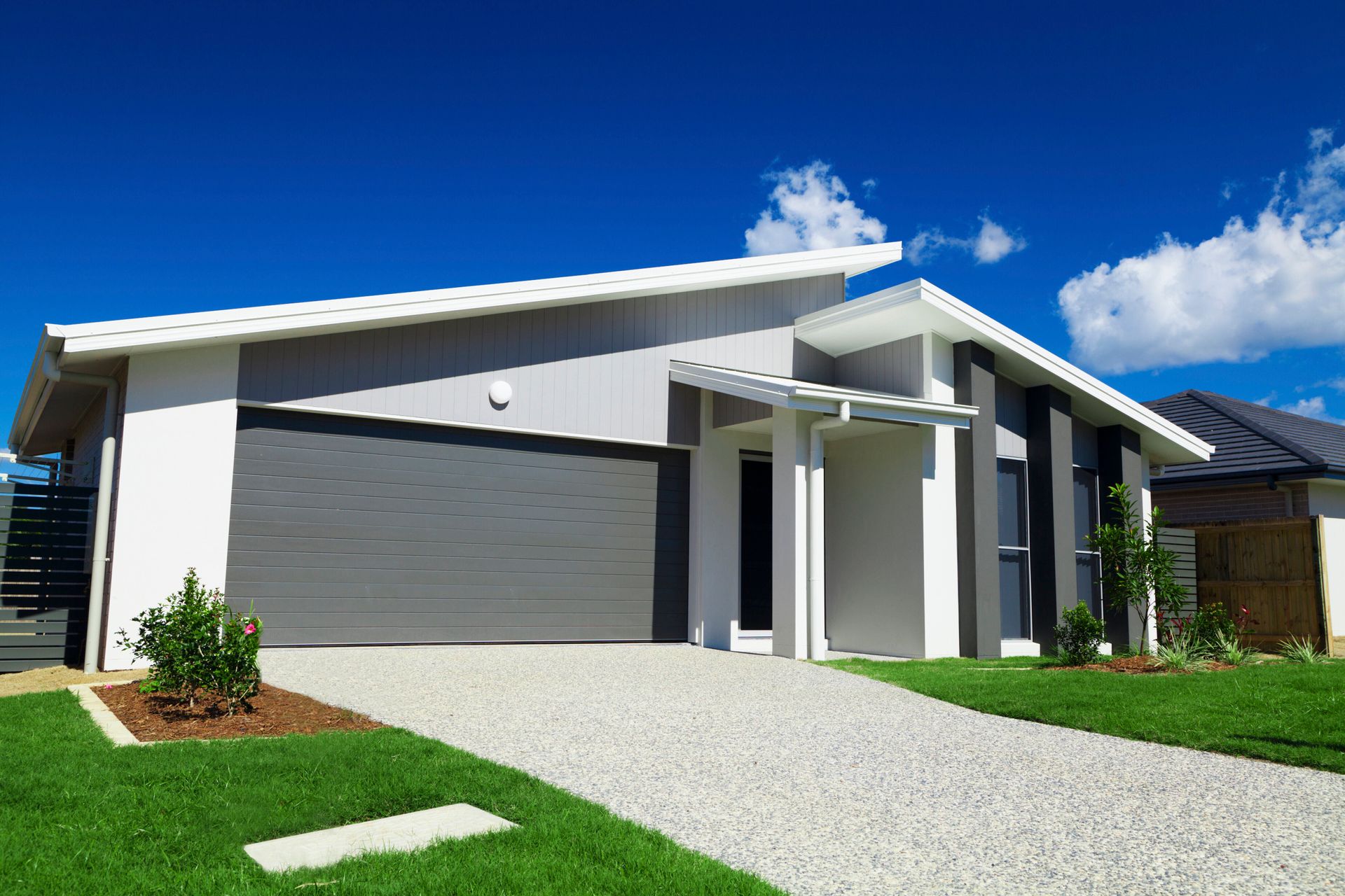Modern house with gray garage door and a blue sky background.