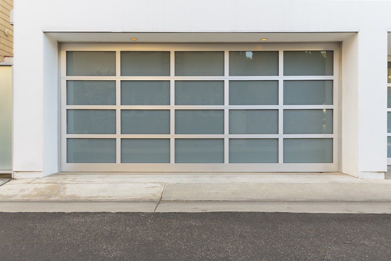 White, grid-paneled garage door with frosted glass and a concrete threshold in front of a white building.