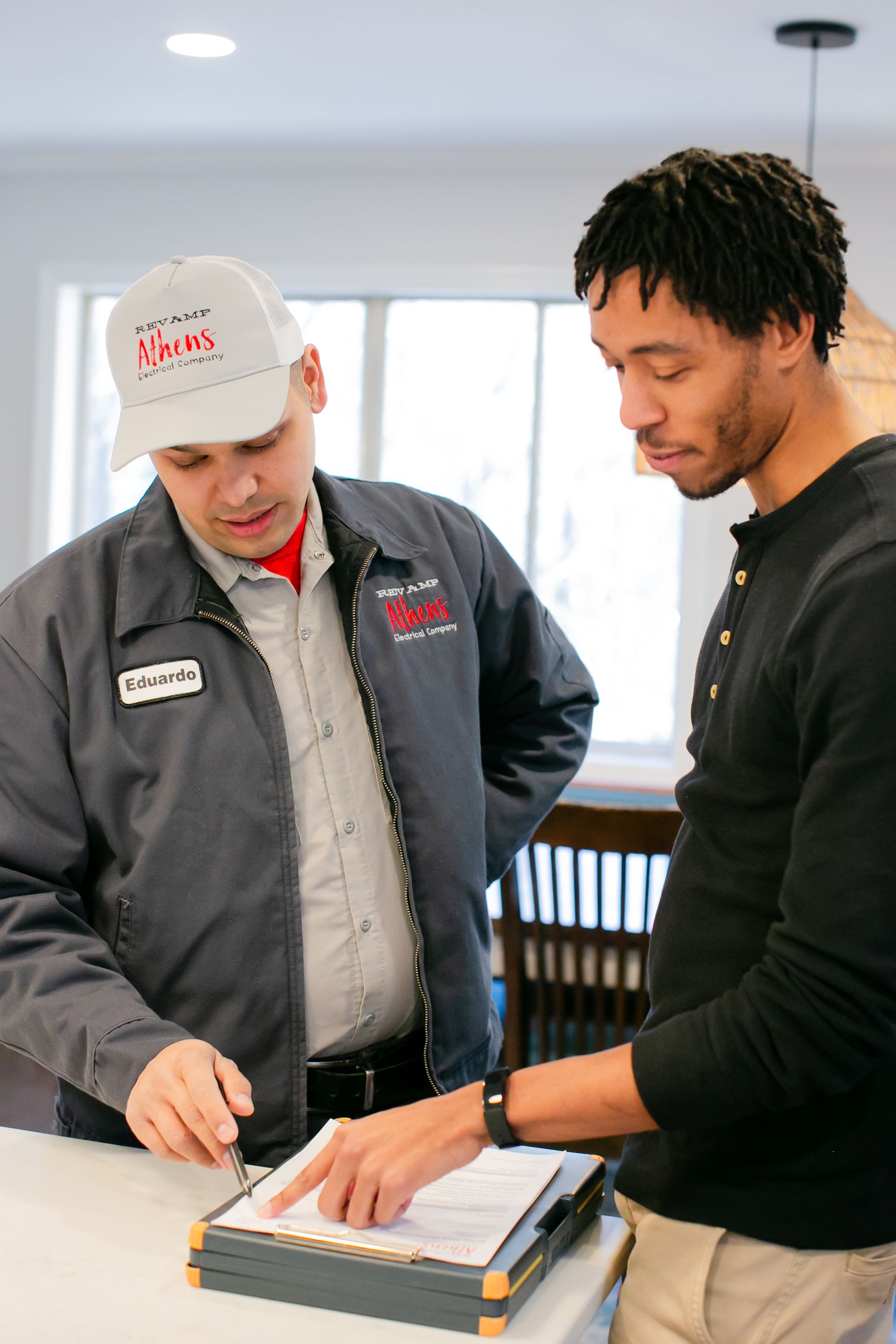 Two men review documents together at a table in a bright office.
