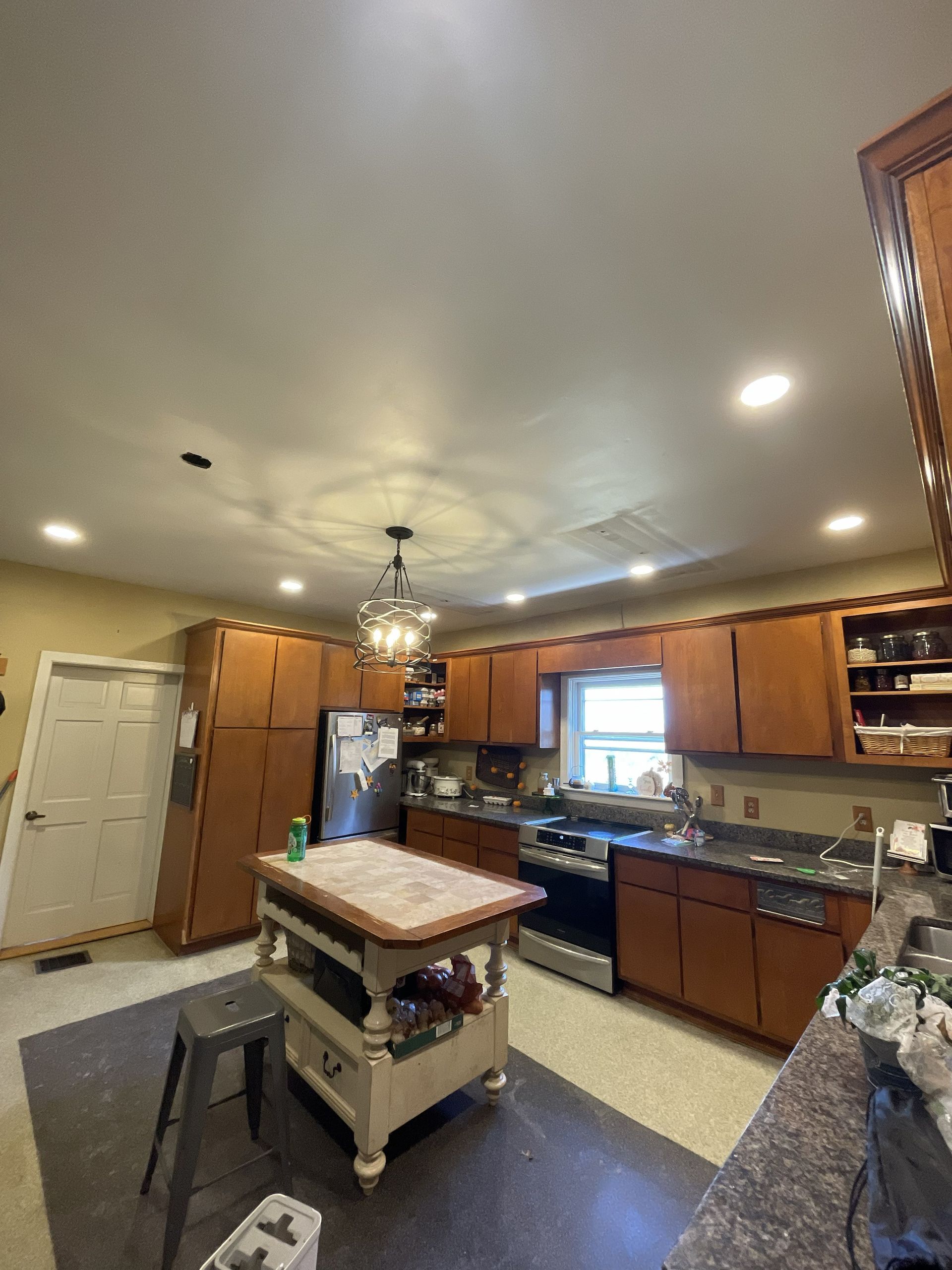 Kitchen with wooden cabinets, white appliances, central island cart, and a window over the sink.