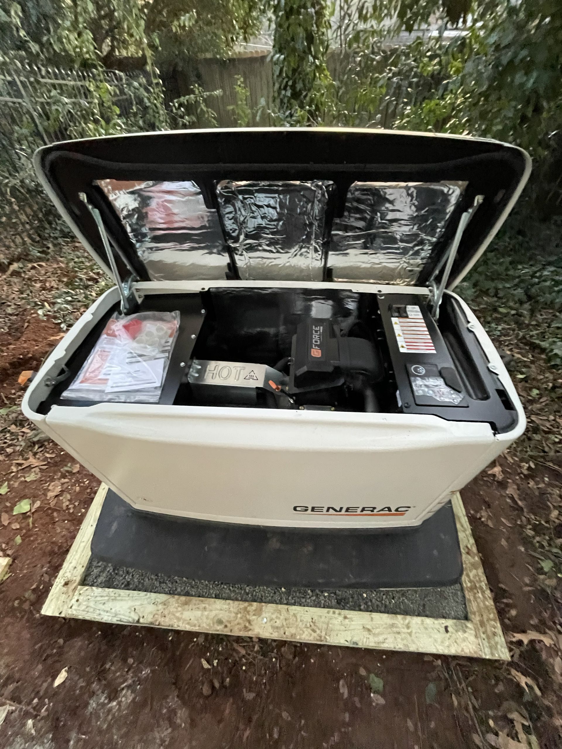 Open white generator with black lid outdoors on a concrete pad