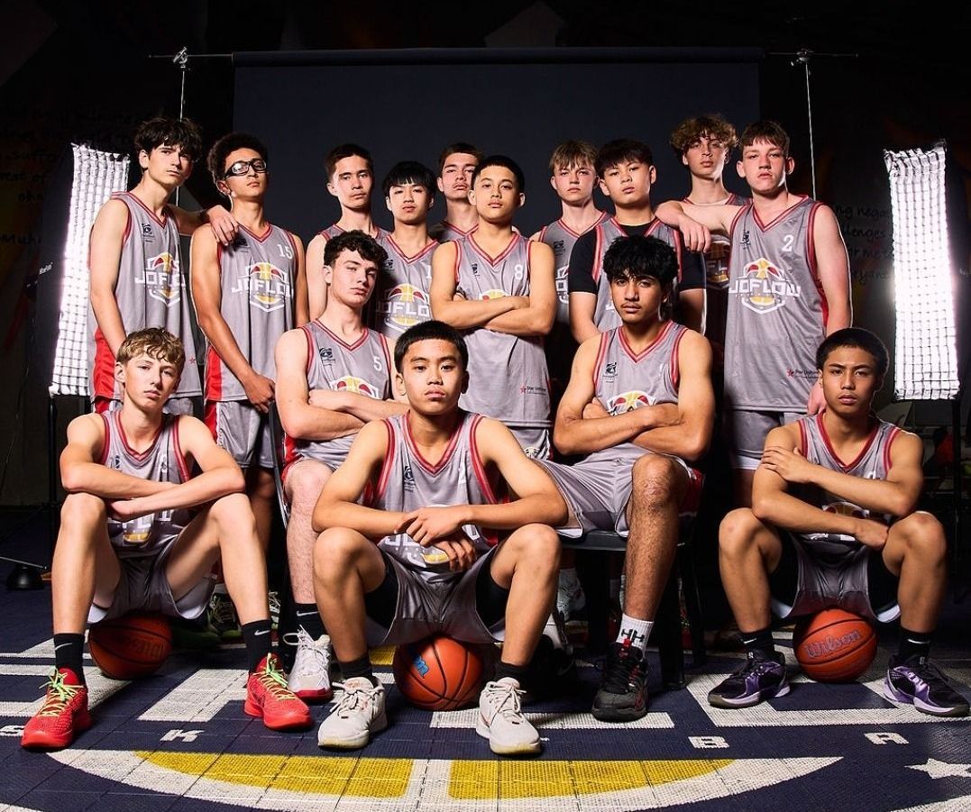A group of young men in basketball uniforms are posing for a picture.