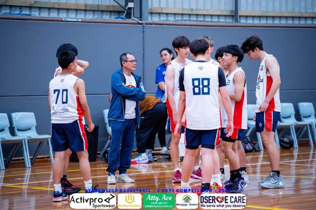 A group of young men are standing in a huddle on a basketball court.